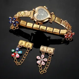 Detail of heart-shaped gold modular watch with floral evil eye charms on steel band