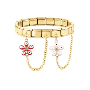Detail of gold modular bracelet with red flower charms and hanging chains in steel