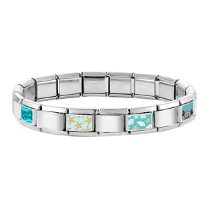 Macro detail of Italian charm bracelet links featuring sea animal patterns and steel stamp