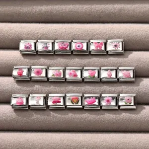Close-up of pink Italian charm links featuring butterfly and floral patterns on steel