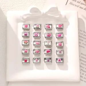 Flat lay of 20 pink Italian charm links with floral and butterfly enamel designs