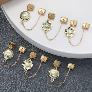 Detail goldener italienischer Charm-Glieder mit Blumenanhängern auf weißen Stufen