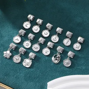 Macro detail of 15 modular silver stainless steel charms with celestial and nautical patterns
