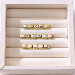 Macro view of modular gold-plated stainless steel charms with pet-themed illustrations