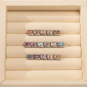 Detail showing modular Italian charms with floral patterns on stainless steel bracelet