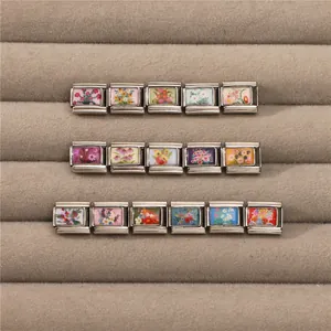 Close-up of DIY Italian charm links with colorful floral patterns on stainless steel