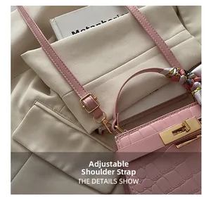 Detail showing the adjustable strap and golden buckle of a pink crocodile texture bag