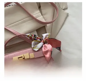 Detail of pink croc-embossed square handbag featuring a gold lock and silk scarf wrap