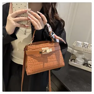 Detail showing brown crocodile pattern leather handbag with metal lock and silk scarf wrap