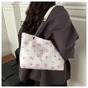 Macro detail of white textured tote bag with pink floral and bow pattern and chain strap