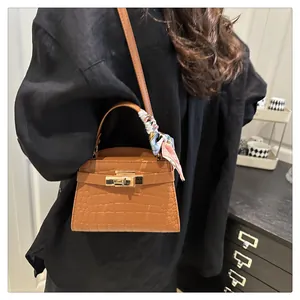 Close-up of brown crocodile pattern square handbag with silk scarf on the handle