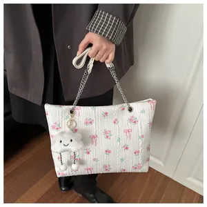 Detailed close-up of floral tote bag with silver chain strap and plush cloud charm