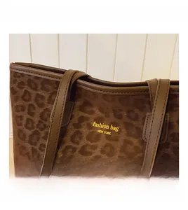 Détail du sac cabas léopard avec anses en cuir marron et décoration en texte doré