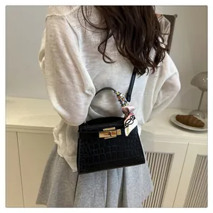 Detail of black crocodile pattern bag with golden swivel lock and printed silk scarf