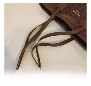 Détail d'un sac cabas à imprimé léopard avec design à double fermeture et anses en cuir