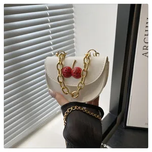 Dettaglio borsa a spalla bianca con catena dorata e accessorio ciliegia in 3D