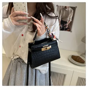 Detail of black crocodile texture bag with gold twist lock and floral handle scarf