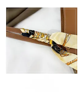 Détail de la bandoulière en cuir marron avec surpiqûres blanches et foulard en soie