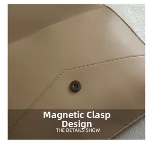 Detailed macro shot of the metal magnetic snap closure on a minimalist leather envelope bag