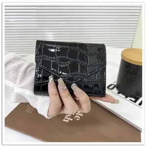 Close-up of black crocodile embossed patent leather envelope card holder held in hand
