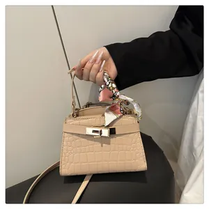 Close-up of crocodile pattern leather handbag with metal lock and silk scarf handle