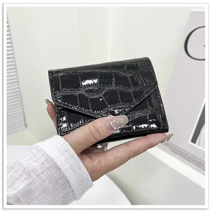 Detail of glossy black crocodile embossed trifold envelope wallet held in hand