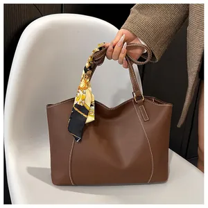 Détail d'un sac cabas en cuir marron avec surpiqûres blanches et un foulard en soie