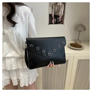 Detail of minimalist black clutch bag with silver eyelets on a V-shaped flap