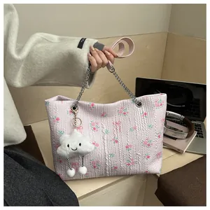 Detail of pink floral bucket bag with quilted texture, silver chain and cloud plush charm