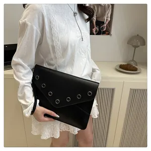 Detail view of black envelope clutch bag featuring silver metal eyelets and a hand strap