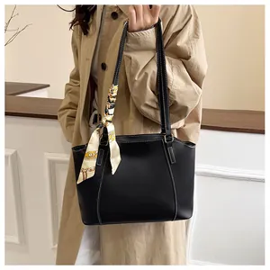 Détail du sac trapèze noir avec surpiqûres blanches et poignée en foulard de soie géo