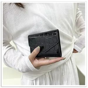Close-up of elegant black patent leather envelope clutch with crocodile embossing textures