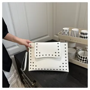 Detail of white leather envelope clutch with stylish square metal studs and wrist strap