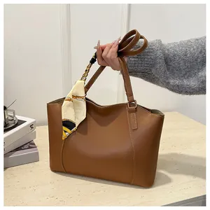 Détail de ce sac cabas en cuir marron avec foulard en soie imprimé décoratif sur l'anse
