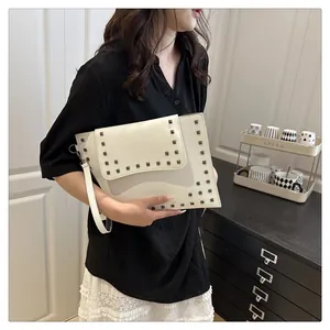 Detailed macro view of white envelope clutch bag with grey square metal rivets and wrist strap
