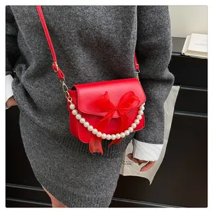 Detailansicht rote PU-Lederhandtasche mit Organza-Schleife und weißer Perlenkette