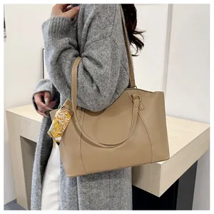 Détail d'un grand sac cabas beige avec deux anses et un foulard en soie décoratif porté
