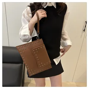 Close-up of brown envelope clutch bag featuring silver studs and detachable leather strap