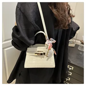 Detailed view of white crocodile pattern bag with gold clasp and floral silk scarf handle