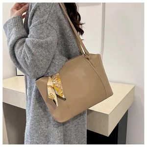 Détail d'un sac cabas en simili cuir kaki avec un foulard décoratif en soie à motifs jaunes