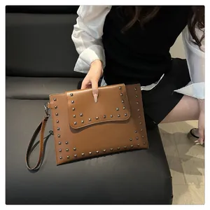Detailed close-up of brown leather envelope clutch with silver square rivets and wristlet