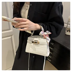 Detailed close-up of white croc-effect mini bag with gold buckle and silk scarf