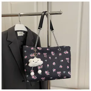 Detail of black floral tote bag with pink butterfly prints and a cute plush cloud charm