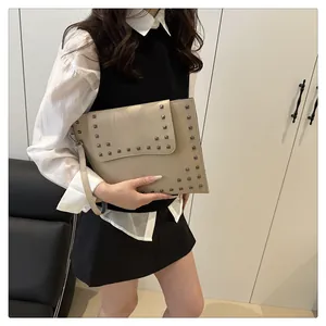 Detail of beige envelope clutch bag featuring silver square studs and matching wrist strap