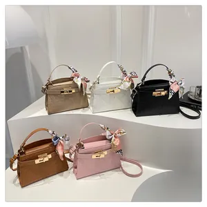 Detailed view of crocodile pattern crossbody bags with colorful silk scarf handles and gold clasp