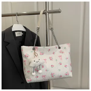 Detail of white jacquard bucket bag with pink rose patterns and cloud plush charm