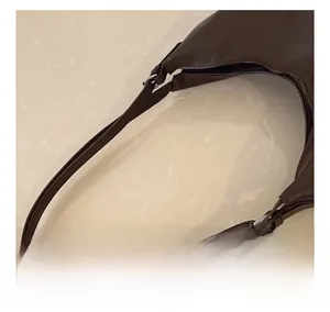 Detail of adjustable shoulder strap with silver buckle on dark brown leather tote bag