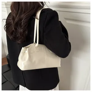 Detailed side view of a cream white shoulder bag on a model wearing a black tweed jacket