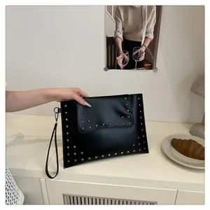 Detail of a black matte leather envelope clutch with silver square studs and a wristlet