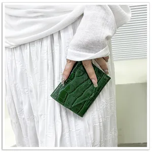 Close-up of deep green crocodile embossed patent leather envelope wallet held in hand
